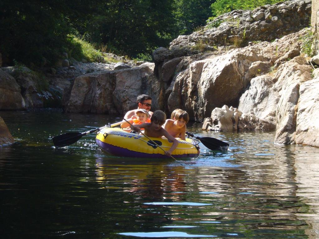 Un homme et deux enfants dans un radeau sur une rivière dans l'établissement Gîtes de Neyrac, appartement Violette - piscine, rivière à 100 m, vue sur les collines, à Meyras