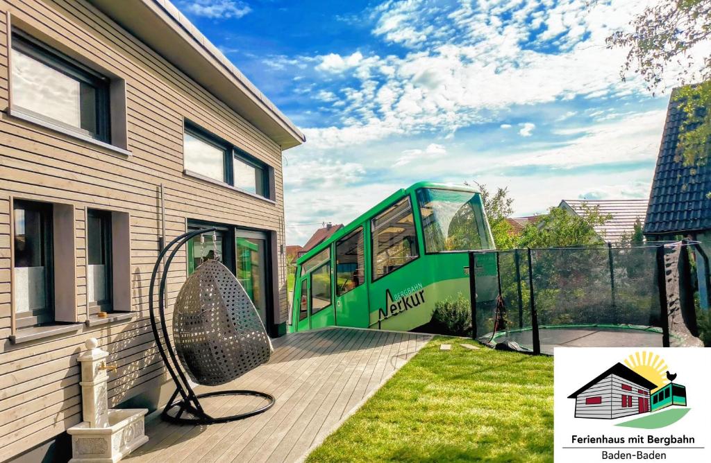 un autobús verde estacionado en una terraza junto a una casa en Exklusives Holzhaus mit Bergbahn - Baden-Baden im Schwarzwald, en Baden-Baden