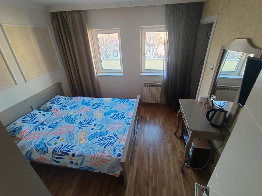 a bedroom with a bed and a desk and two windows at 塞尔维亚悦客之家民宿 in Belgrade