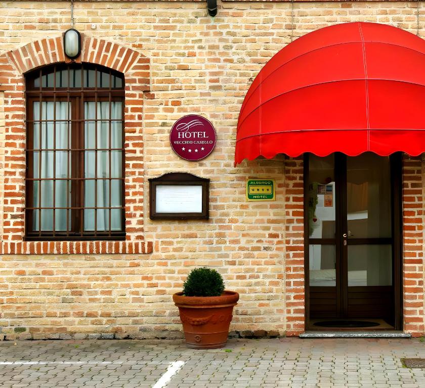 a brick building with a red umbrella and a potted plant at Hotel Vecchio Casello in Castelleone