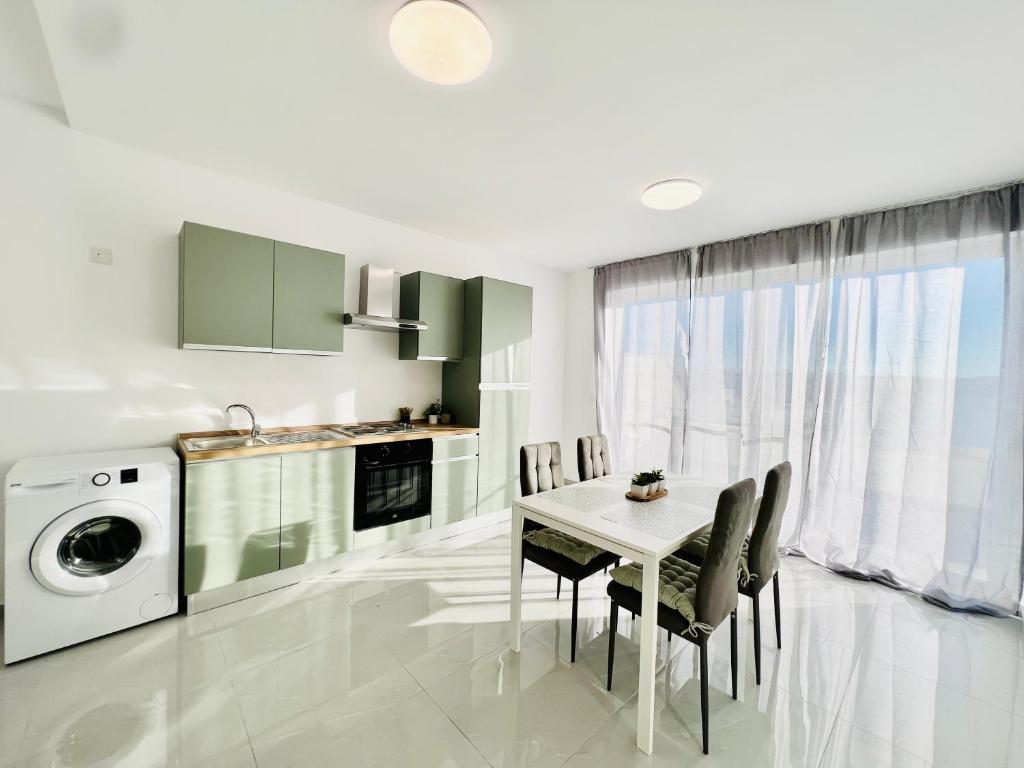 una cucina con tavolo, sedie e lavatrice di SUNSHINE SUITS - BRAND NEW APARTMENTS a Msida