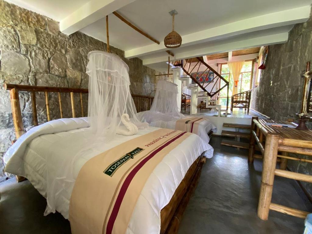 a bedroom with two beds and a stone wall at Cabañas Tosepan Kali in Cuetzalán del Progreso