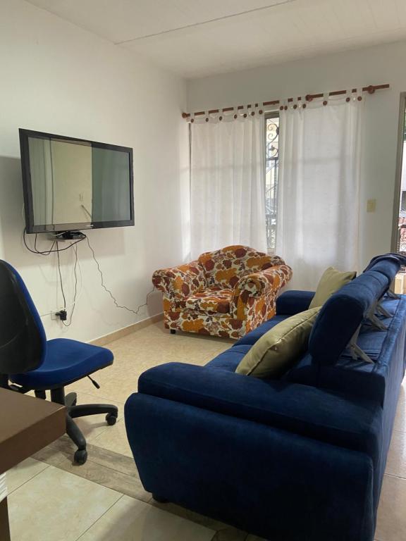 ein Wohnzimmer mit einem blauen Sofa und einem TV in der Unterkunft apto caney 301 in Cali