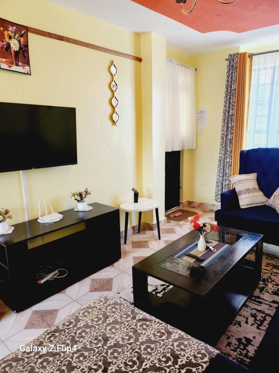un soggiorno con un divano blu e una TV di Cosy 1 Bedroom TRM,Thika Rd a Nairobi