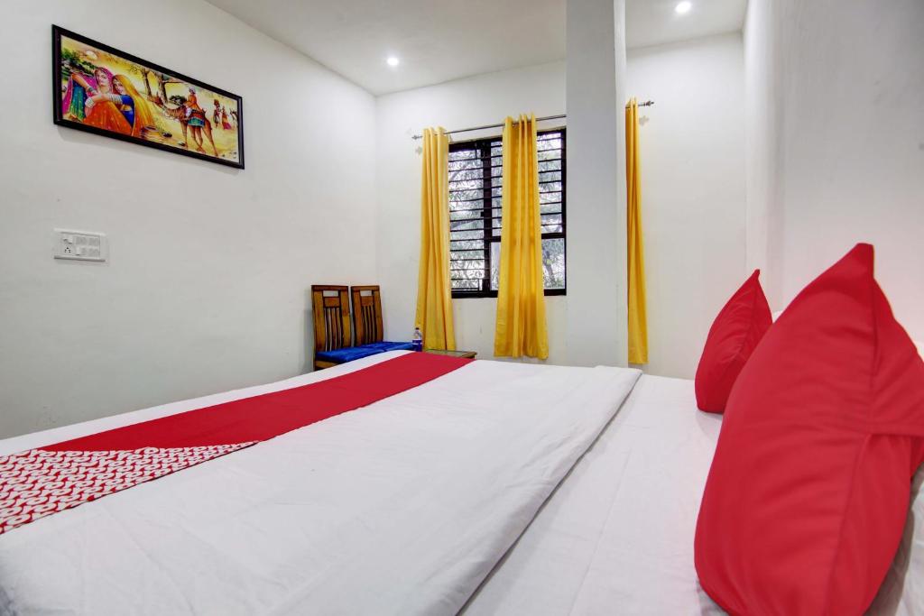 a bedroom with a large white bed with red pillows at Super OYO Flagship Blossom Inn Burari in New Delhi