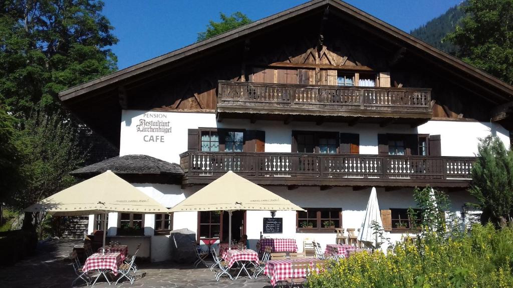 a building with a balcony and tables and chairs at Landhotel Lärchenhügel in Oberammergau