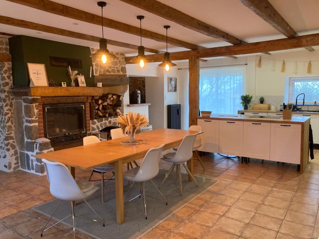 uma grande cozinha com uma mesa de madeira e cadeiras em La maisonnée Auvergnate em Auzelles
