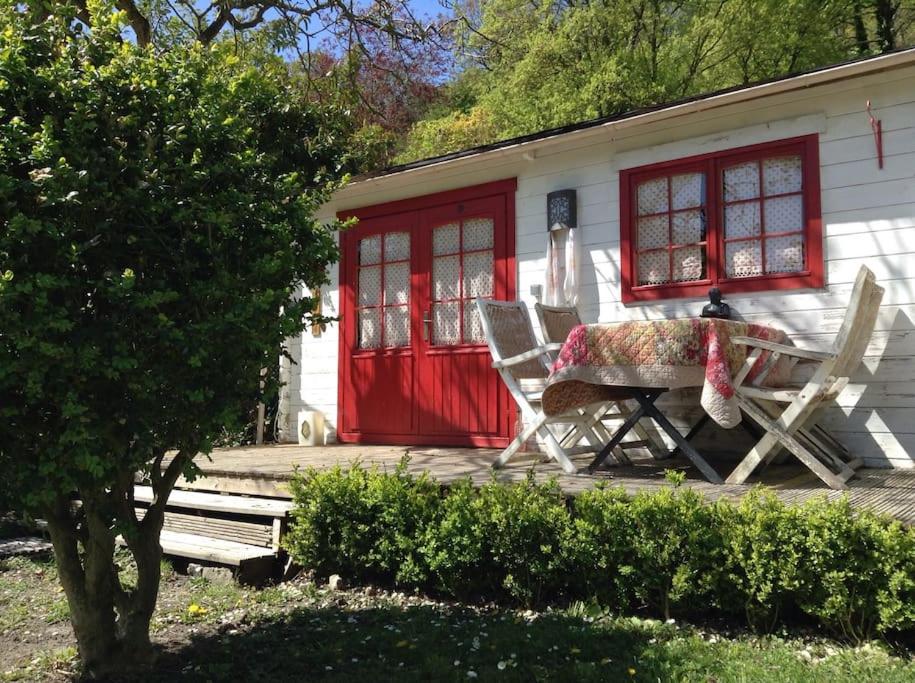 une maison avec une porte rouge, une table et des chaises dans l'établissement Le Paradis caché : Chalet Shangri-La, à Villennes-sur-Seine