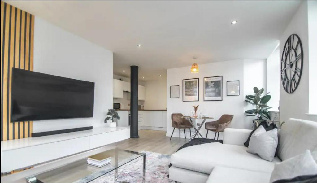 uma sala de estar com um sofá branco e uma televisão de ecrã plano em Conditioning House - Suite 1 em Bradford