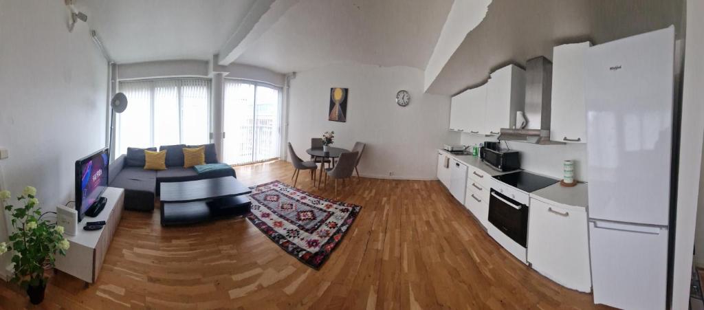 Solace Apartment, Oslo Downtown في أوسلو: غرفة معيشة كبيرة مع أريكة ومطبخ