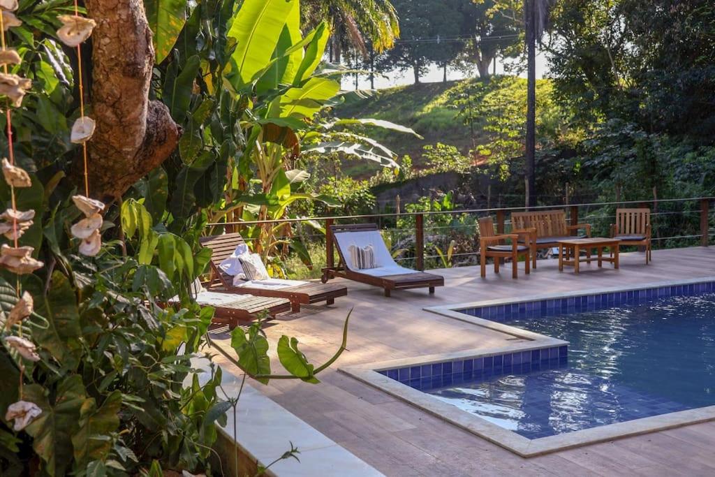 a swimming pool with chairs and a table next to at Casa Amadou com grande piscina em Boipeba in Ilha de Boipeba
