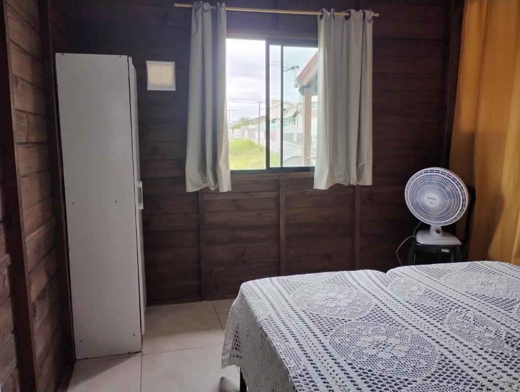 a bedroom with a bed and a window and a fan at Casa das Embaúbas 5 in São José