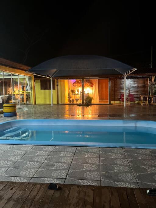 a blue swimming pool in front of a building at night at Bem vindos a Vila da Paz Itaara in Itaara