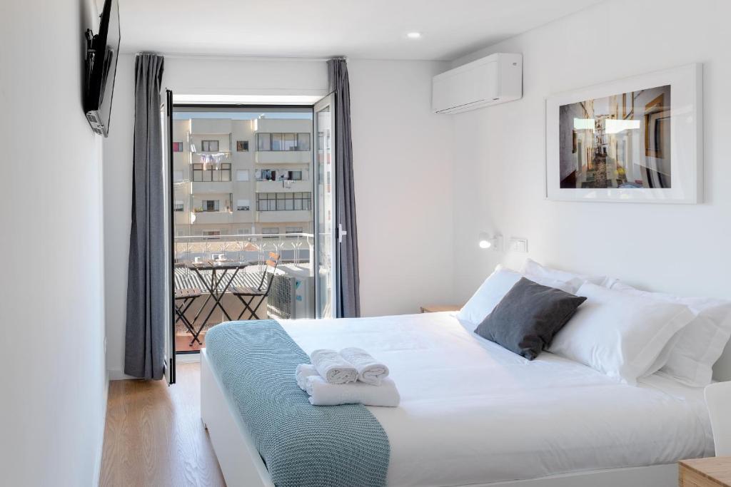 a bedroom with a white bed with towels on it at East River - T4 junto ao Altice Forum - Braga in Braga