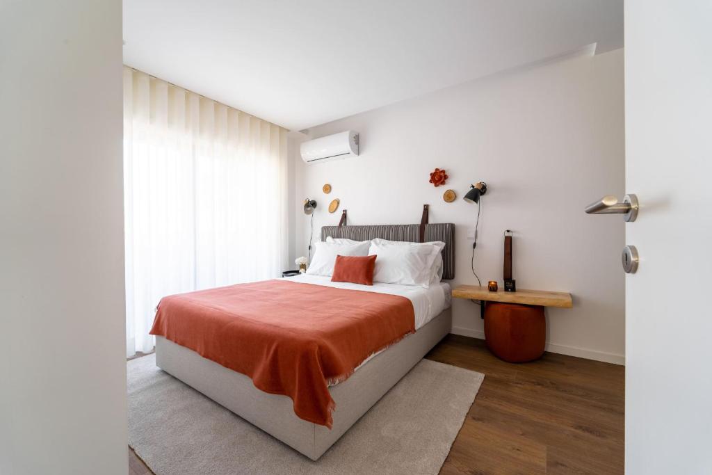 um quarto com uma cama com um cobertor laranja em João da Ponte - T1 Altice Forum Braga by House and People em Braga