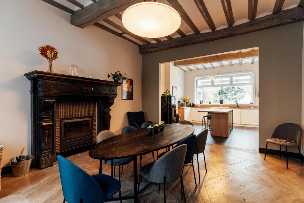 ein Wohnzimmer mit einem Tisch, Stühlen und einem Kamin in der Unterkunft Maison d'hôte Brasserie Caulier in Péruwelz