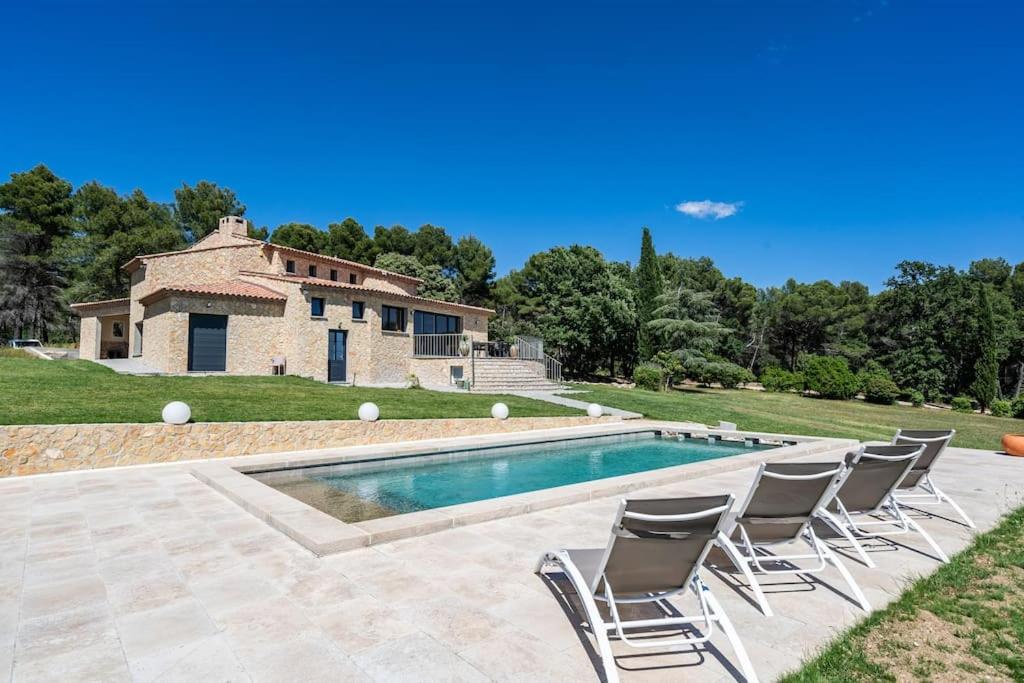une piscine avec des chaises et une maison en arrière-plan dans l'établissement Villa avec tennis & piscine, 10min Aix-en-Provence - Villa Les Vignes, à Puyricard