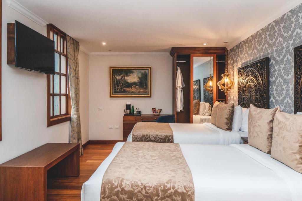 a hotel room with two beds and a flat screen tv at Hotel Cruz del Vado in Cuenca