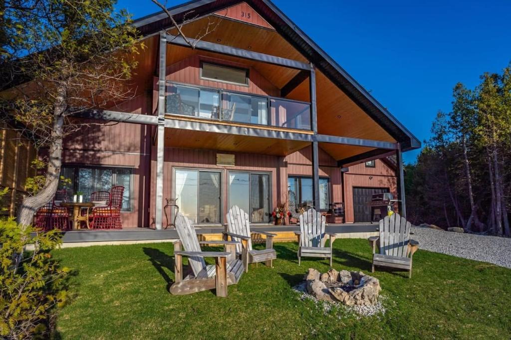 a house with chairs and a table in the yard at Lakefront Luxury Cottage - Shining Star - Close to Sauble Beach in Wiarton