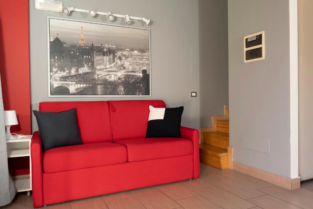 - un canapé rouge dans le salon avec une photo dans l'établissement Easy Space, à Bientina