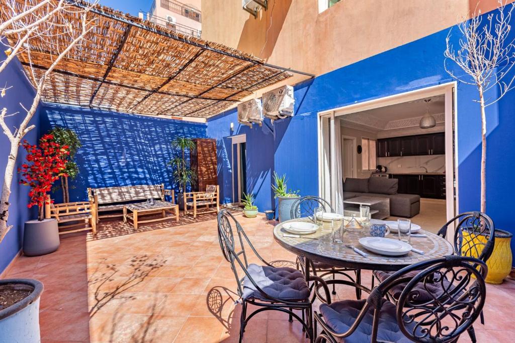 a patio with a table and chairs and a blue wall at Coin de verdure et détente. in Marrakesh