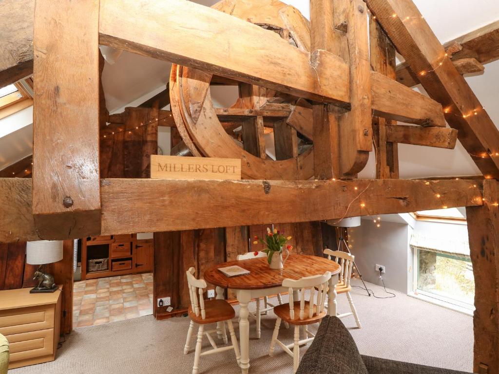 a dining room with a wooden ceiling with a table and chairs at Millers Loft in Llanrwst