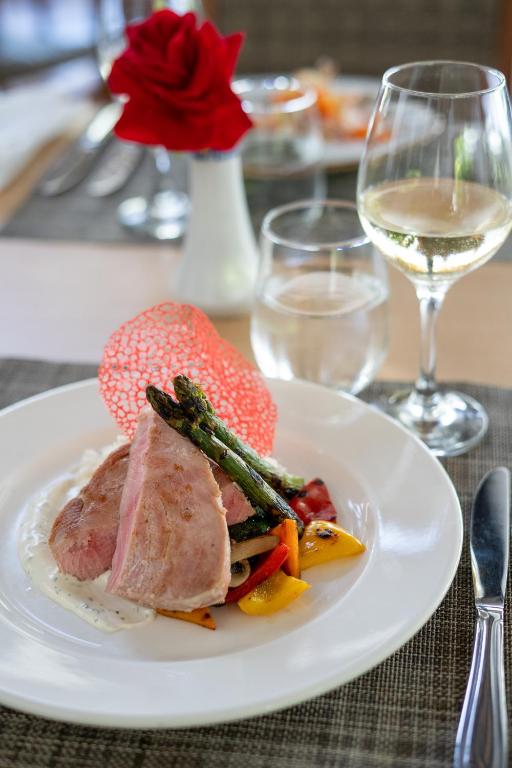 a white plate with meat and vegetables and a glass of wine at Impressive Premium Punta Cana - All Inclusive in Punta Cana