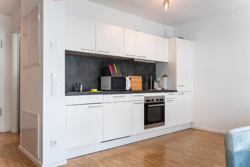 een witte keuken met witte kasten en een magnetron bij Modernes 1 Zimmer Apartment im Zentrum Offenbachs in Offenbach