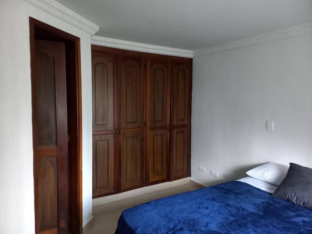 sypialnia z drewnianymi szafkami i niebieskim łóżkiem w obiekcie APARTAESTUDIO DETRAS DE UNICENTRO w mieście Armenia