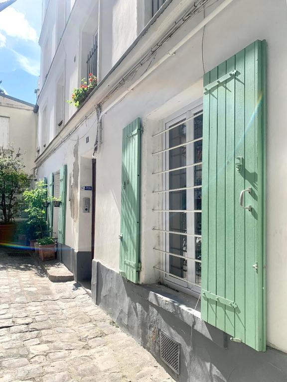 Une allée avec des portes vertes dans un bâtiment dans l'établissement Charmant 2 pièces Paris Montmartre, à Paris