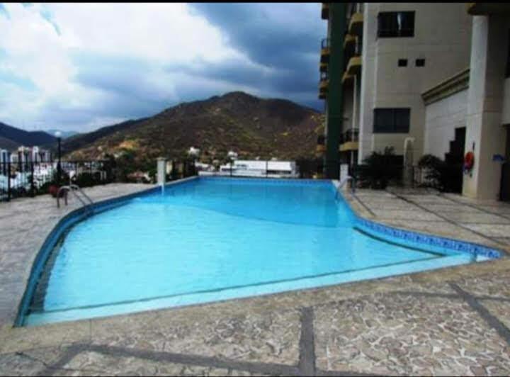 a large blue swimming pool in front of a building at El Peñón frente al mar in Gaira