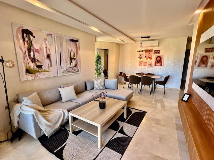 una sala de estar con un sofá y una mesa en New appart, pool and golf view, en Marrakech