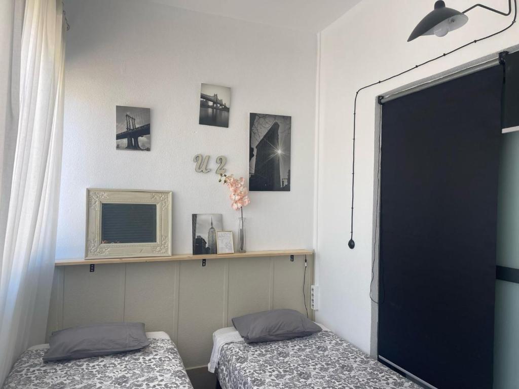 - une chambre avec 2 lits et une télévision sur une étagère dans l'établissement Glass Student-Übica2 Guesthouse, à Mairena del Aljarafe