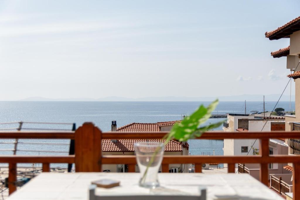 a table with a glass on a balcony with the ocean at Casa Del Mar in Neos Marmaras