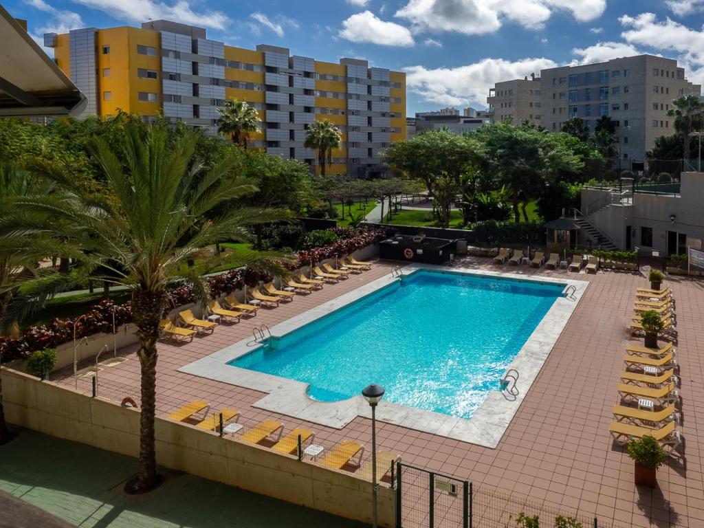 una piscina con tumbonas y un complejo en Apartment Abora Garden with terrace, pool, extensive gardens and free parking, en Las Palmas de Gran Canaria