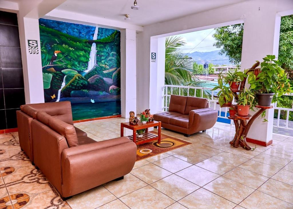 ein Wohnzimmer mit 2 Stühlen und einem großen Gemälde in der Unterkunft HOSPEDAJE LA MERCED in Juanjuí