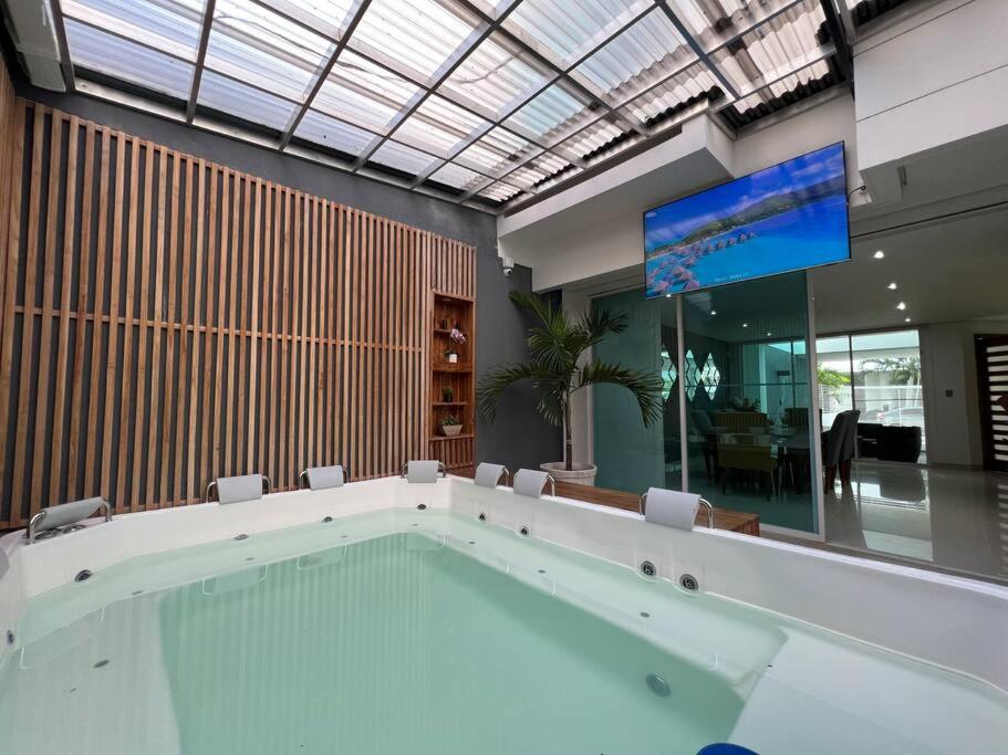 a large swimming pool in a room with a tv at Lujosa Casa con jacuzzi CastilloGrande in Cartagena de Indias