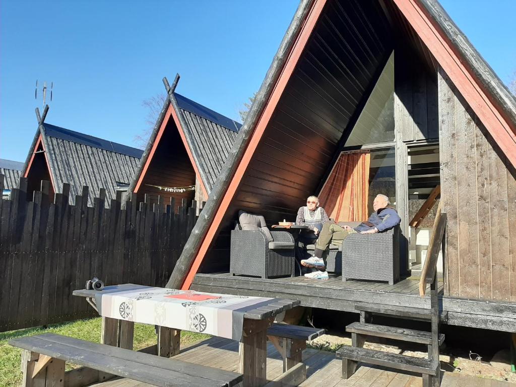 zwei Männer an einem Tisch vor einem Haus in der Unterkunft Hallingparken in Gol