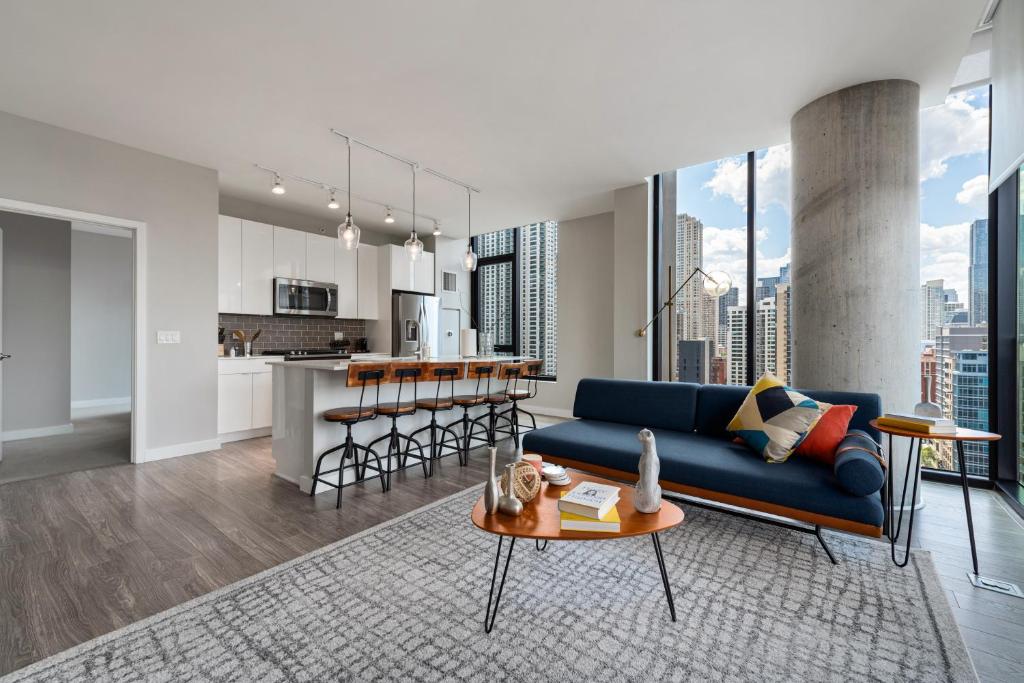 a living room with a blue couch and a kitchen at Aurelien Spacious Apartments in the Heart of Gold Coast in Chicago