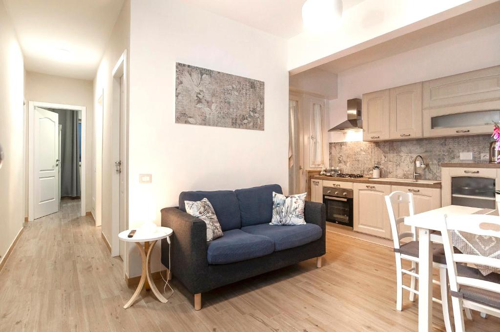 a living room with a blue couch and a kitchen at Elegant comfy three-room apartment in Eur with parking in Rome