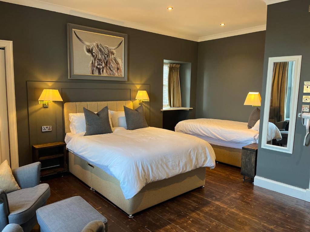 a bedroom with two beds and a chair and a mirror at Fraser House in Inverness