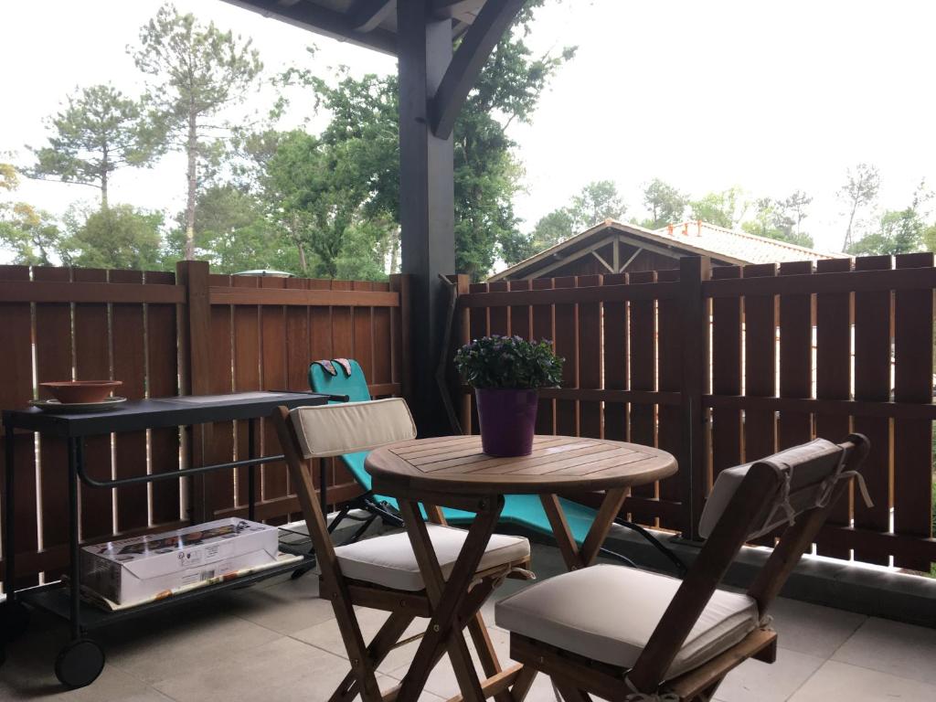 una mesa y sillas en un patio con una valla en T2 avec grand balcon en Labenne
