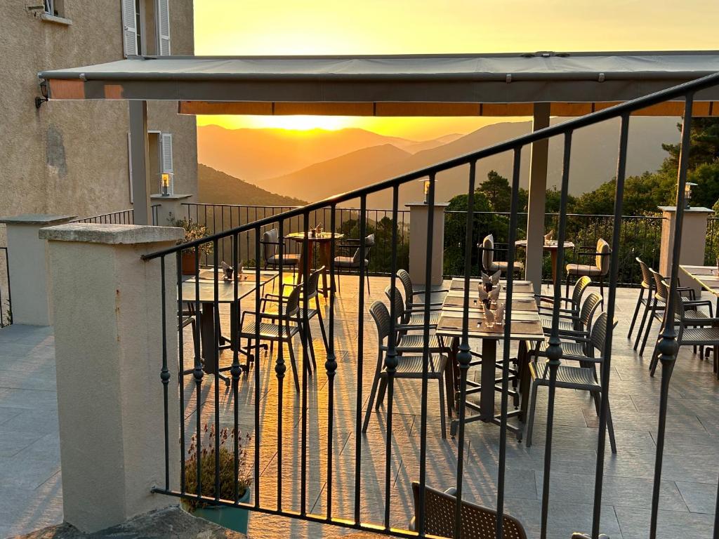 een tafel en stoelen op een balkon met uitzicht op de zonsondergang bij Hôtel U Frascone in Venaco