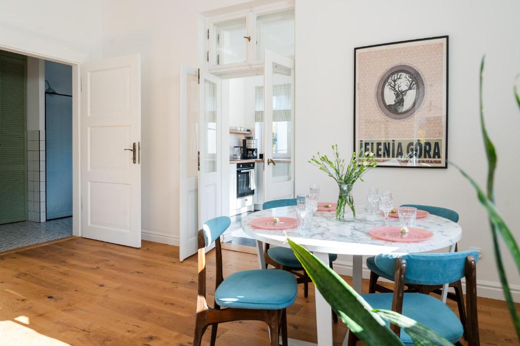 a dining room with a white table and blue chairs at Apartament VinyLove - blisko Parku Zdrojowego i Term - by Space Apart in Jelenia Góra