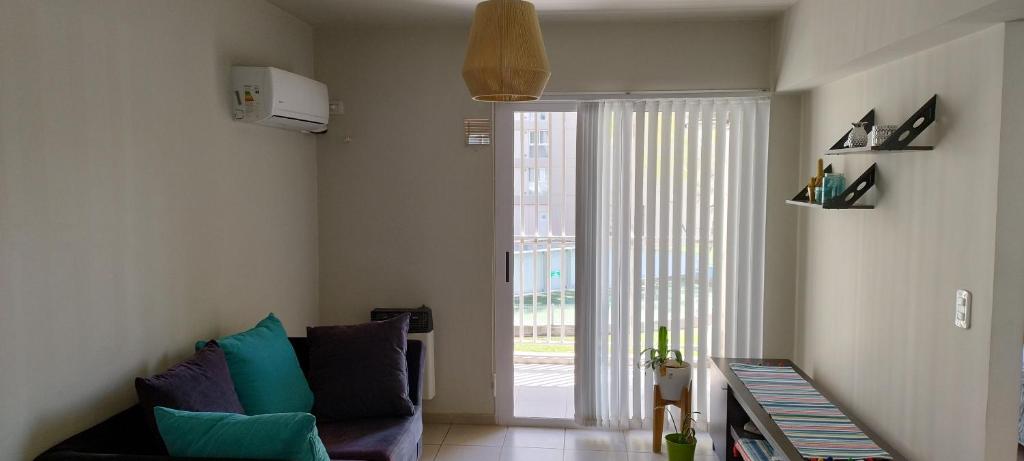ein Wohnzimmer mit einer Couch und einer Glasschiebetür in der Unterkunft Del vino departamento in La Cieneguita