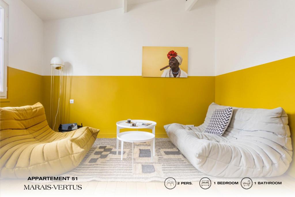 a yellow room with two beds and a table at Beauquartier - Marais Vertus in Paris