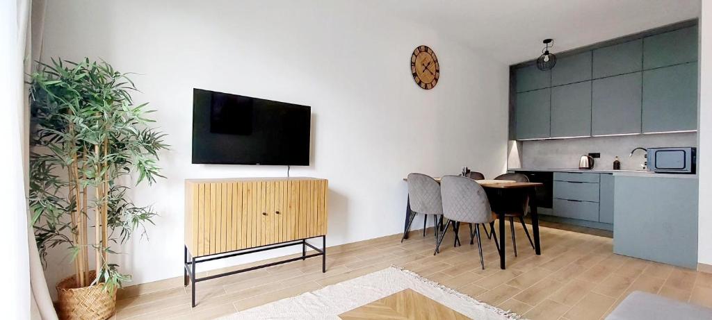 a living room with a table and a tv on a wall at Panorama Garden in Olsztyn