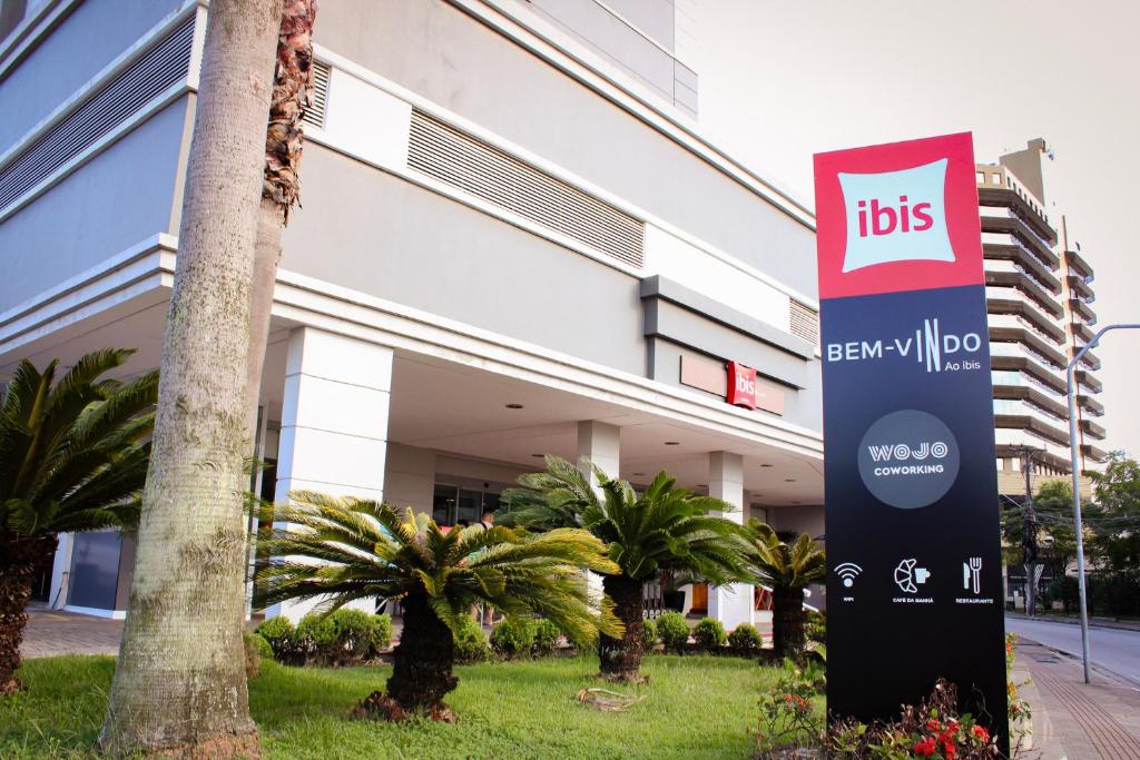 ein Schild vor einem Gebäude mit Palmen in der Unterkunft ibis Sao Jose in São José