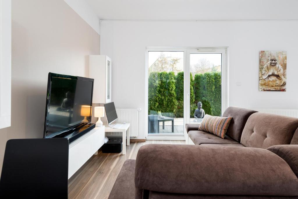 a living room with a couch and a flat screen tv at Apartment Kozielska z pięknym ogrodem i tarasem in Gliwice