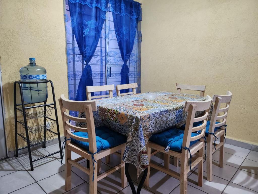 a dining room table and chairs with a blue curtain at Casa Latania in El Salto